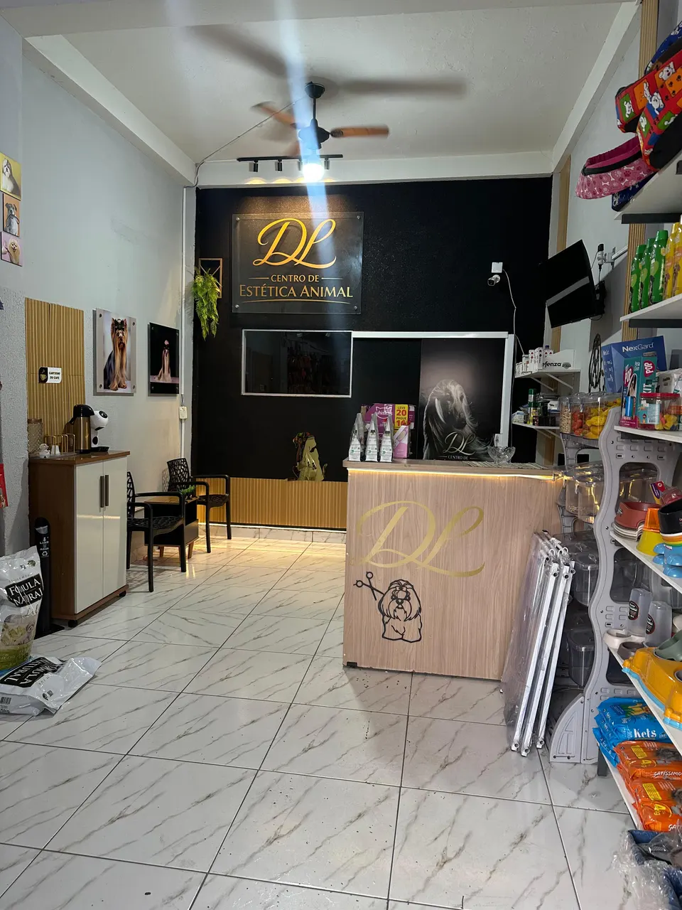 Interior da loja com prateleiras de produtos, recepção e parede com o logotipo da DL